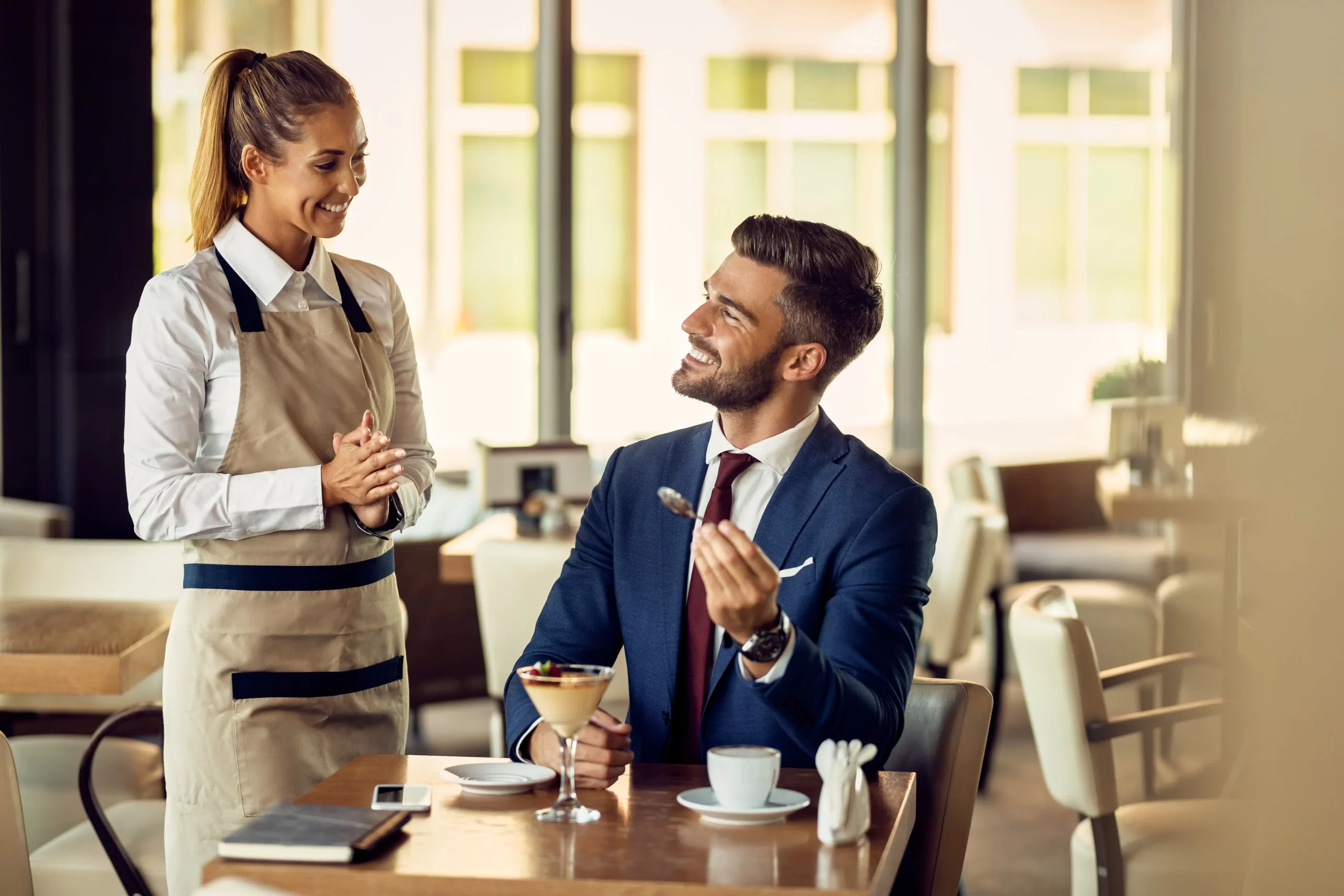 young-happy-waitress-talking-businessman-cafe-min